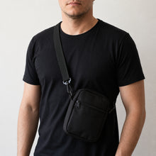 Close da shoulder bag preta no peito, mostrando o caimento da alça