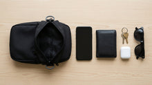 Shoulder bag preta vista de cima, ao lado dos objetos que cabem dentro